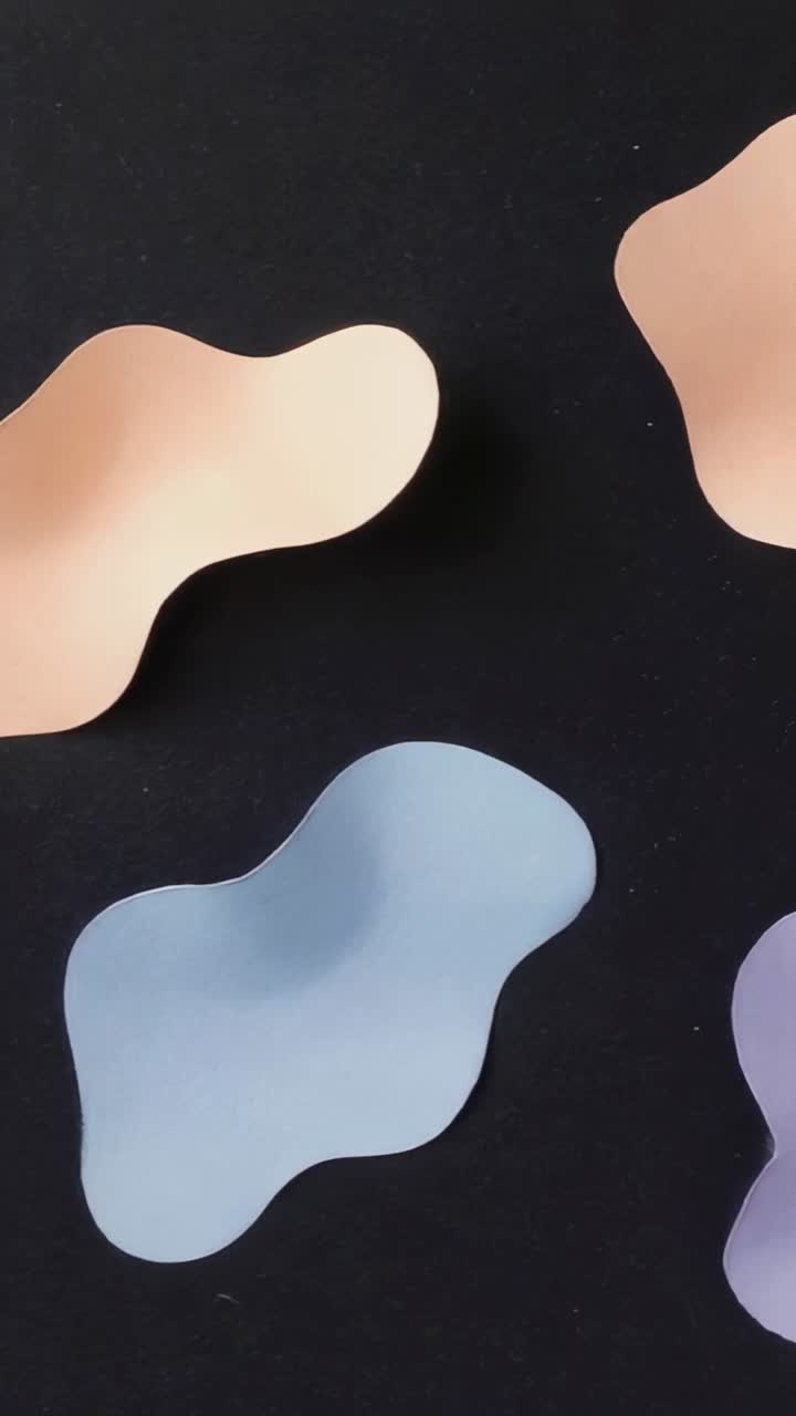Vertical video: Starting four flat shapes drifting on black backdrop, looping motion