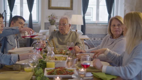 familia feliz sentada a la mesa en el comedor, hablando juntos y disfrutando de la comida en casa