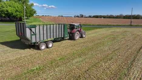 Wide-lens-aerial-tracking-shot-of-Massey-Ferguson-tractor-pulling-full-silage-trailer