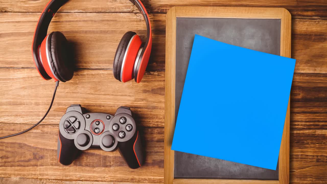 Animation of memo note with copy space over chalkboard, joystick and headphones on desk