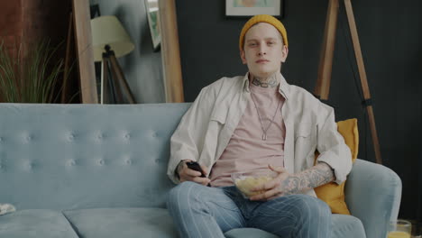 man relaxing on couch watching tv with chips