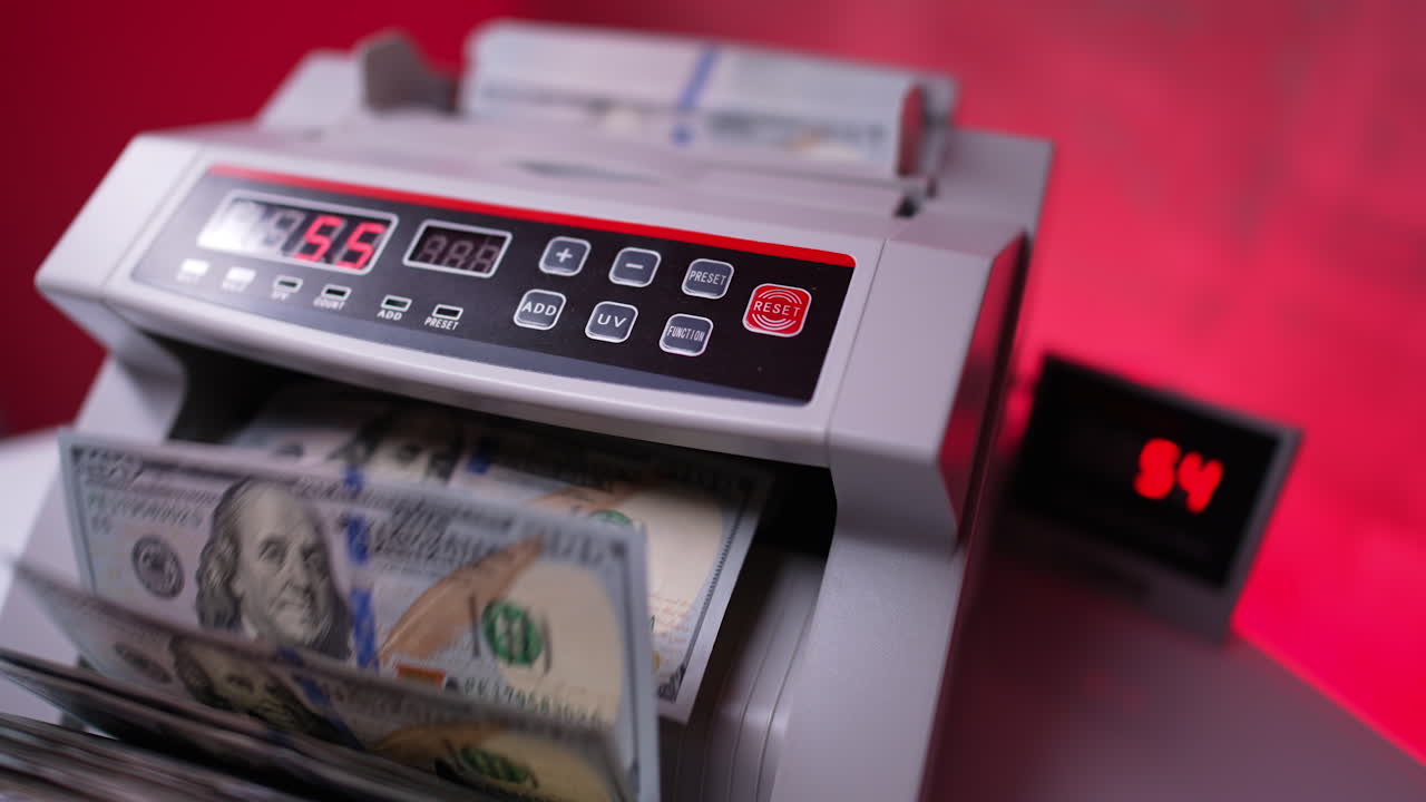 One hundred dollar banknotes rotated in cash counting machine. Close up. Red blurred backdrop.