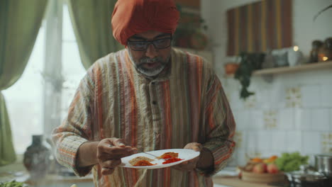 indian food blogger adding aromatic spices to dish while cooking in kitchen