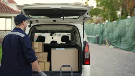 una mujer conoce a un hombre de entrega atractivo y amigable que le da una caja de paquetes al lado de su casa. concepto de mensajero, entrega a domicilio