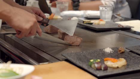 japanese chef cooker show guest authentic kobe wagyu meat while searing over teppanyaki table at japan restaurant osaka japan