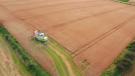 drone footage of golden fields and combine harvester