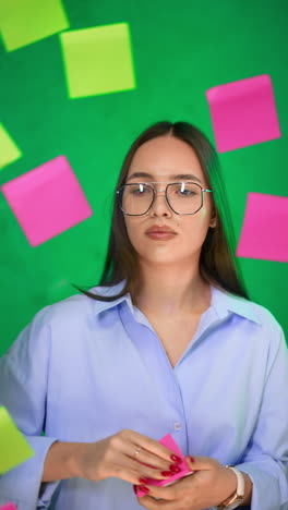 young caucasian lady in glasses and shirt puts colorful stickers on the glass board. financial presentation concept. vertical video.