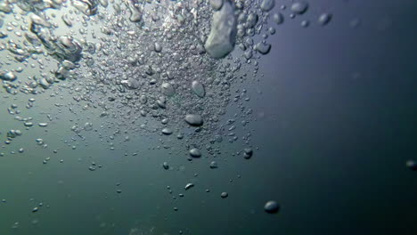 cinematic underwater shot of air bubbles in slow motion in dark waters