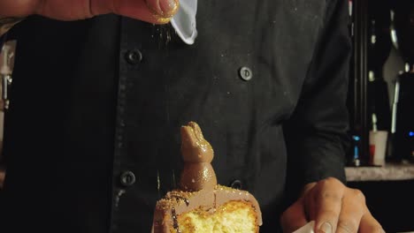 barista masculino latino decorando un pastel de chocolate en un plato blanco con purpurina dorada comestible en un restaurante cafetería en méxico américa latina