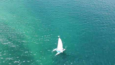 a aerial view of a small sailboat in the blue of the caribbean waters on a sunny day