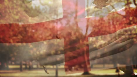 Digitale-Komposition-Von-England,-Das-Die-Flagge-über-Mehreren-Herbstblättern-Schwenkt,-Die-Gegen-Den-Park-Fallen