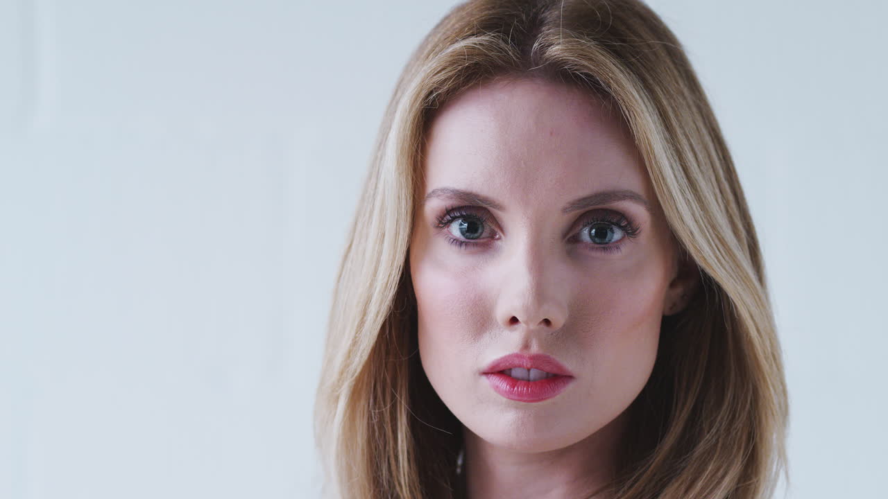 색 스튜디오 벽에 서 있는 결단력 있는 젊은 여성의 패션 초상화