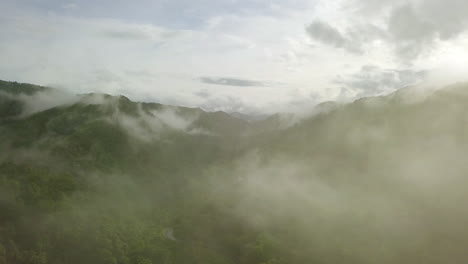 Aerial-view-flying-thru-the-morning-rain-cloud-covered-tropical-rain-forest-mountain-landscape-during-the-rainy-season-on-the-Doi-Phuka-Mountain-reserved-national-park-the-northern-Thailand