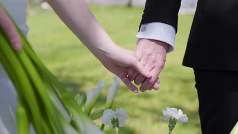 romantic bride and groom holding hands outdoor nature background. close-up shot