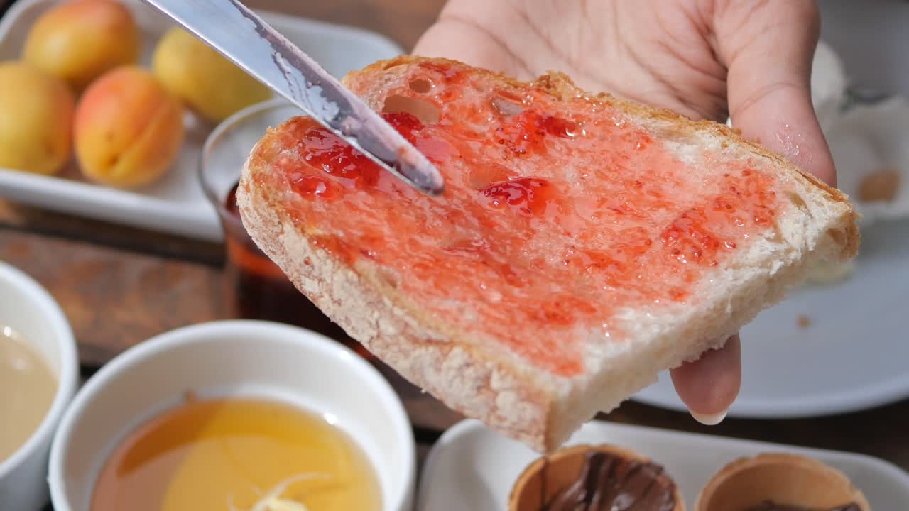 Hand holding a slice of bread with jam