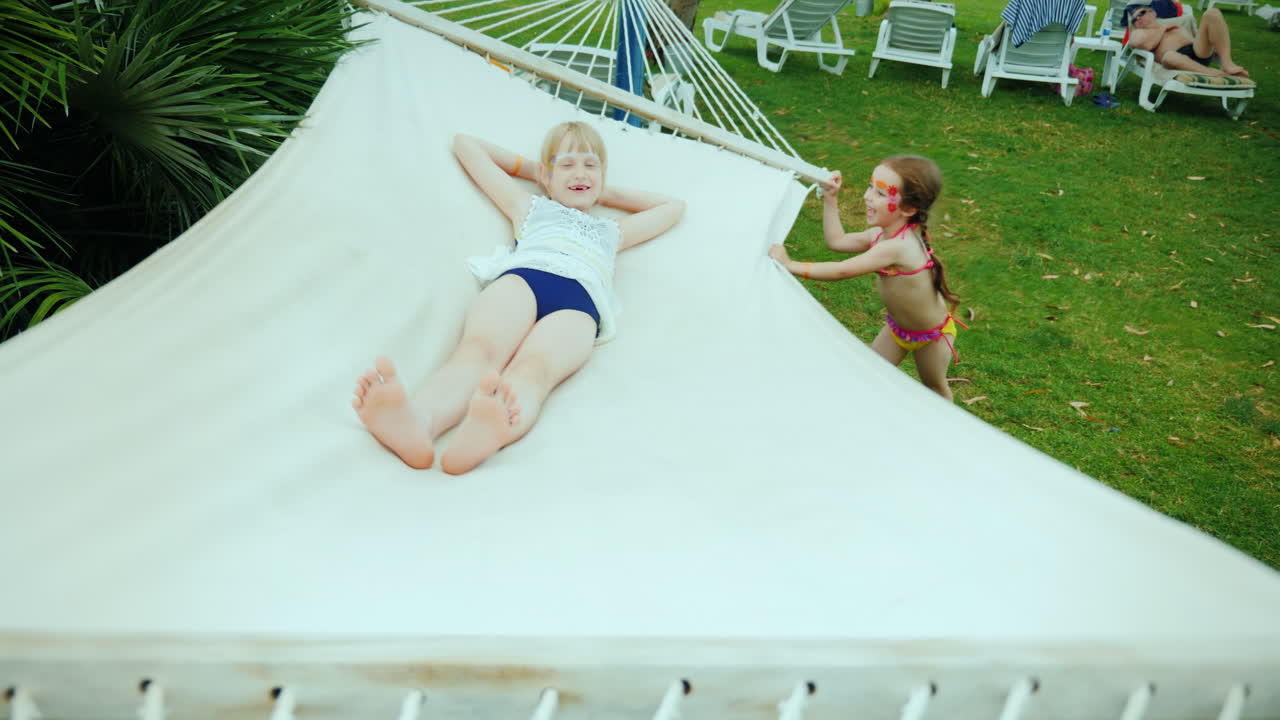dos amigas geniales juegan en el patio de recreo en una hamaca en un resort exótico