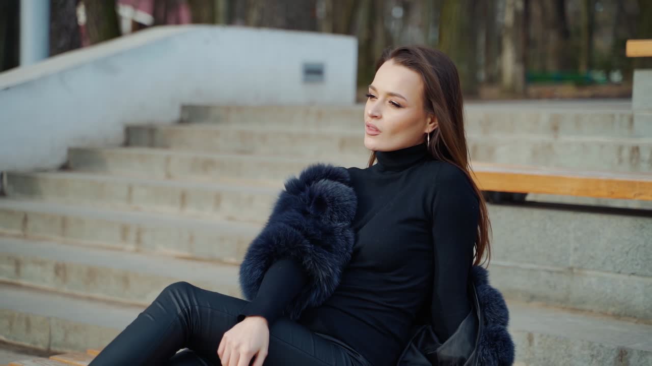 Sexy brunette woman posing wearing dark fur coat looking to tha camera with hands near face. Fashion video.