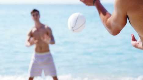 friends playing rugby at beach