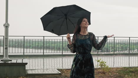 Woman-hides-under-black-umbrella-enjoying-rainy-weather