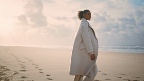 beach woman admiring landscape play with sand. black hair traveler watch waves