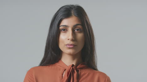 Head-And-Shoulders-Studio-Portrait-Of-Serious-Young-Businesswoman-Against-Plain-Background