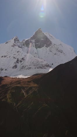 mountain summit on sunny day background with copy space for text, sun shining and snowcapped mountains vertical video for social media instagram reels and tiktok, snowy mountain peak with sunshine