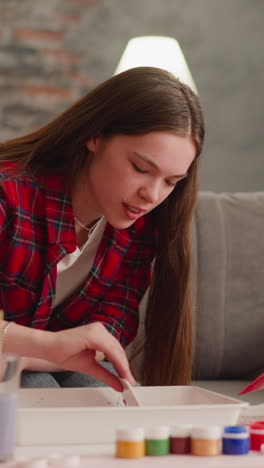 cute child looks attentively at elder sister doing pattern with comb for ebru design in living room slow motion. traditional turkish art practicing