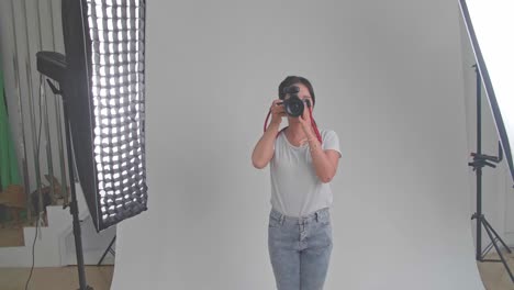 young asian female photographer standing and taking photos in studio