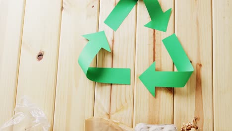 primer plano de la basura y el símbolo de reciclaje de flechas de papel verde sobre fondo de madera, con espacio para copiar