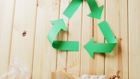 close up of trash and recycling symbol of green paper arrows on wooden background, with copy space