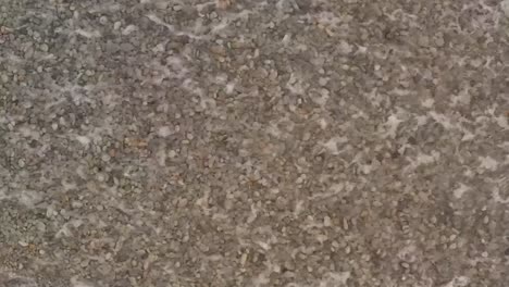 Overhead-Shot-of-Looc-Bay-Shingle-Beach-with-Crashing-Waves-Forming-White-Foam-Patterns