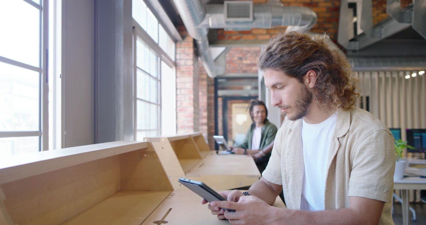African men at counter, one opening tablet tapping stylus for work, other typing laptop, copy space