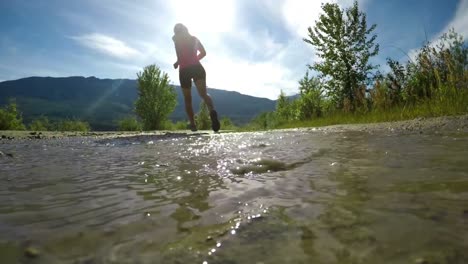 Rear-view-of-fit-woman-jogging-through-puddle-4k