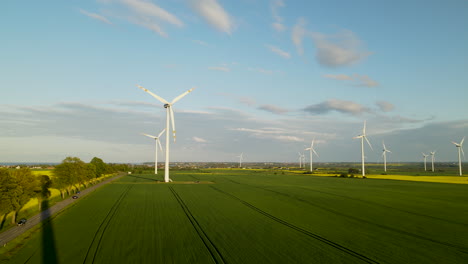 Antenne-Von-Windkraftanlagen,-Die-Sich-Auf-Grünem-Farmfeld-In-Polen-Drehen,-Sonnenaufgang