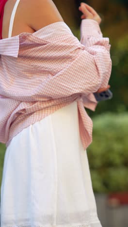 woman wearing a pink gingham shirt over a white dress