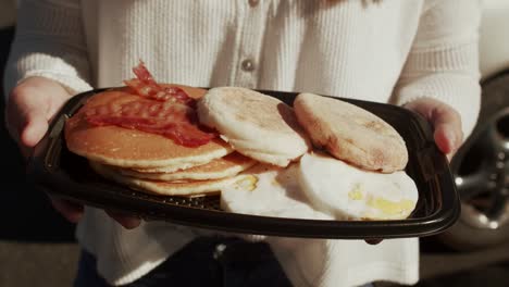 close up of woman holding a breakfast plate with lot of peaces of bead on it