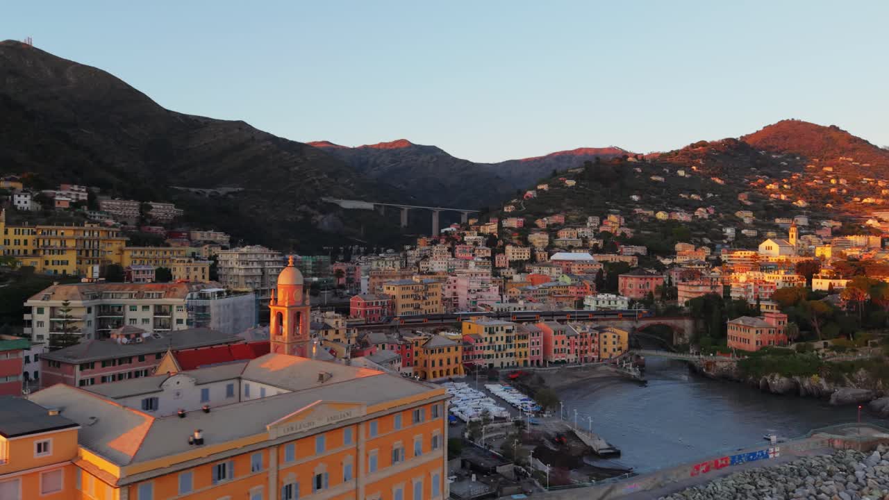 Genoa city with colorful buildings and mountainous backdrop during sunset, aerial view