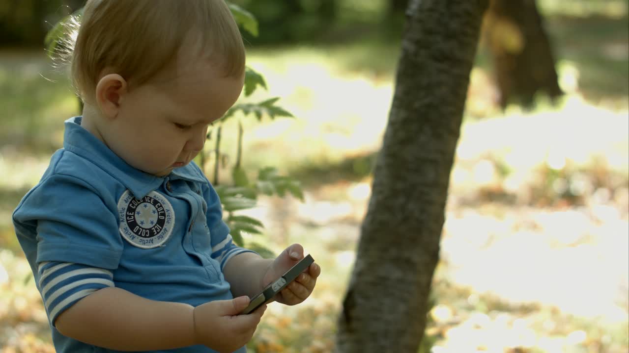 공원에서 스마트폰으로 만화를 보는 사랑스러운 아기