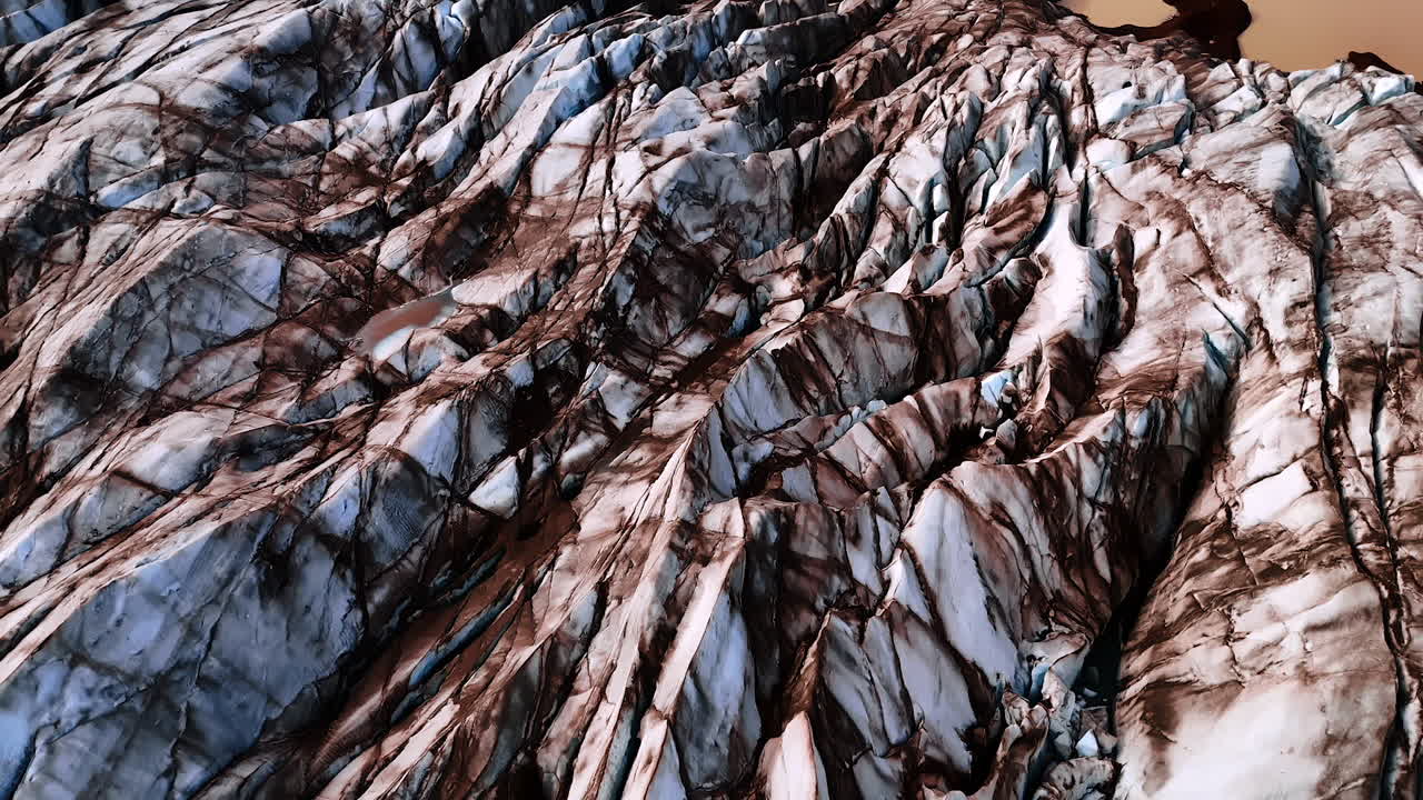 Ancient ices of blue and brown marble-like color. Drone footage above the glacier in Iceland. Approaching a waterscape of cocoa color.