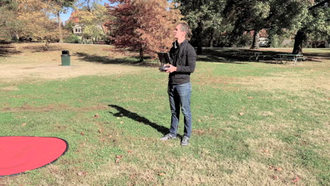un piloto de drones que vuela en el parque escanea el cielo en busca del drone mientras la cámara se acerca a él