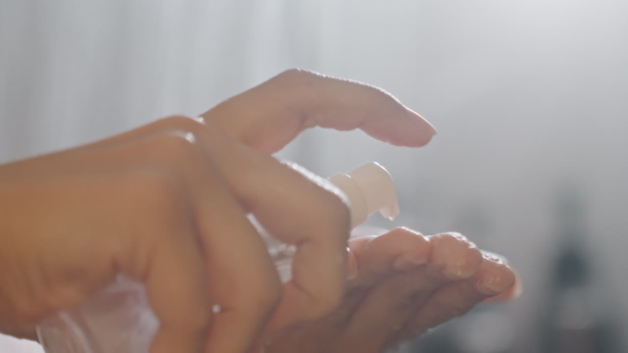 Manos dispensando champú en la ducha del hotel, primer plano de la palma recibiendo líquido de la botella, contraluz suave, formando espuma, textura y movimiento enfocados, cuidado de amenidades para la rutina de higiene del viajero.