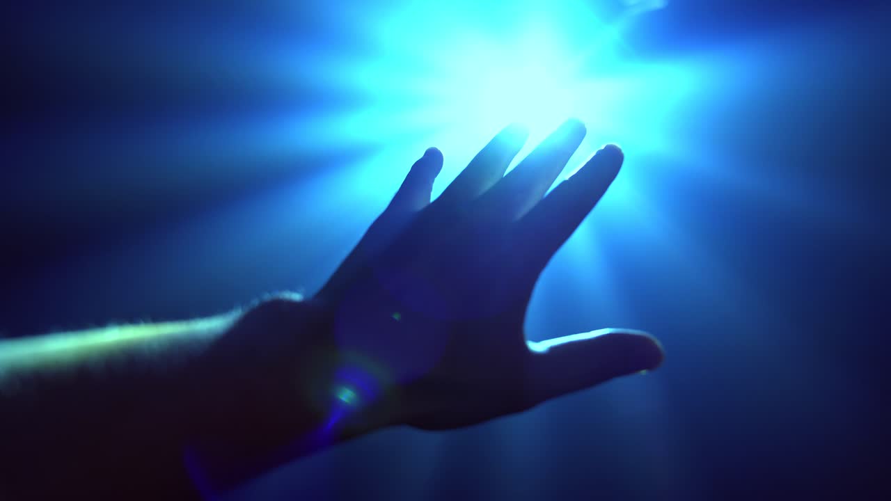 輝くスポットライトをカバーするために手を伸ばす