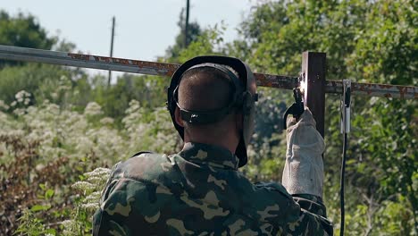 slow-motion-backside-handyman-welds-plank-of-metal-fence