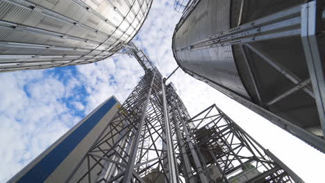 metal construction of a modern agricultural factory. industrial plant for storage and processing seeds. grain elevators outdoors. view from below.