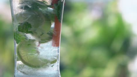 cold mojito in tall glass stands against green background