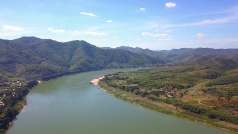 pristine view of famous mekong river surrounded by lush green valleys and mountains under summer blue sky - aerial drone wide shot