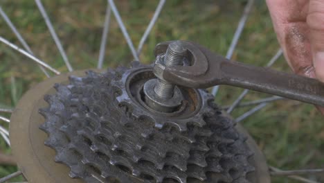 man screws bicycle wheel axle nut