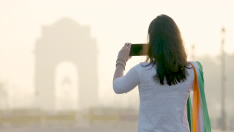 indian girl clicking pictures of india gate in the morning in an indian wear