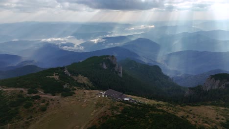 drone circles dochia chalet at sunrise, creating light patterns on trees