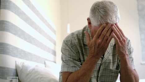 senior man with head ache sitting on the bed